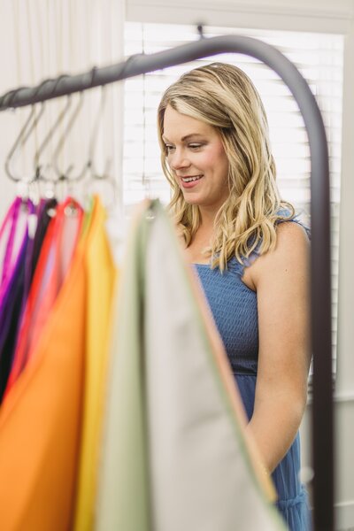 Elizabeth looking at clothes hanging on a rack