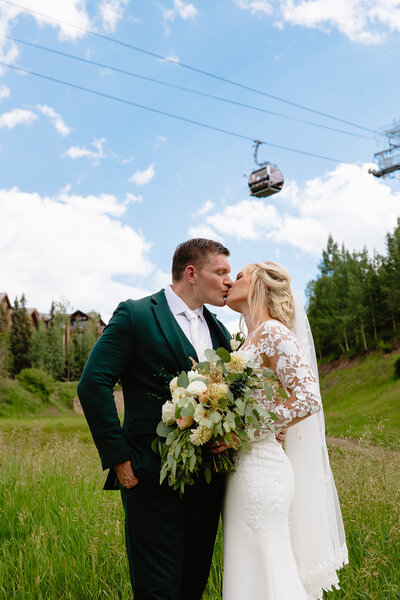 Couple kissing under the Telluride Gondola after an intimate wedding celebration with mountain views