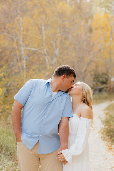 A couple kissing in front of yellow trees in Spearfish Canyon.