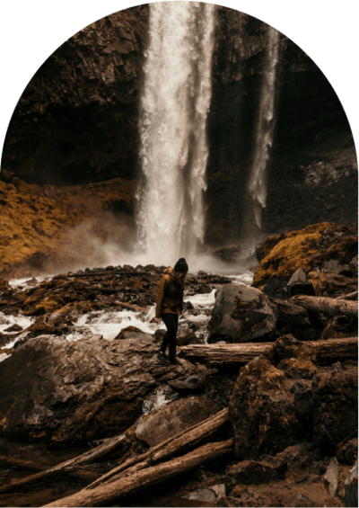 arch photo of woman walking in front of waterfall