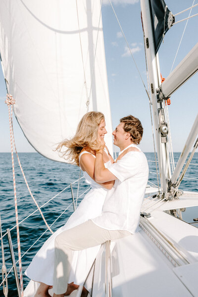 Photo of man and woman sitting on a sailboat in the ocean taken by Elegant wedding photographer Portland Maine