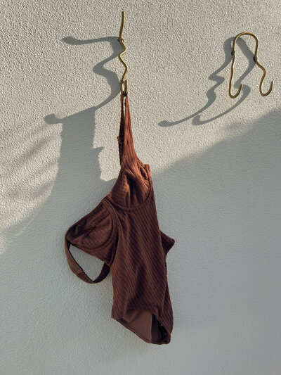 Minimalist swimsuit styling on textured wall, fashion-forward content creation