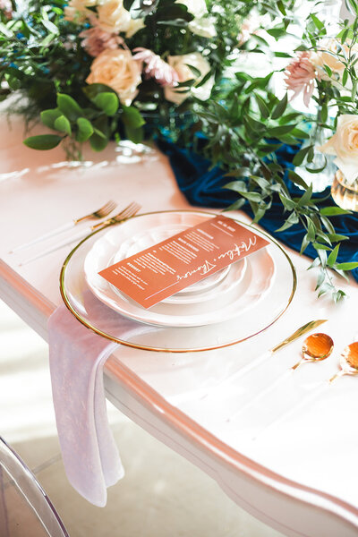 elegant table setting with plate, utensils, menu, and greenery