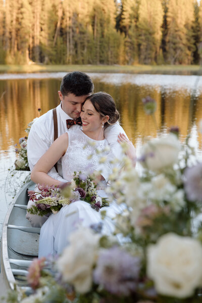 Elopement couple sitting in a canoe decorated with flowers during an elopement in Central Oregon.