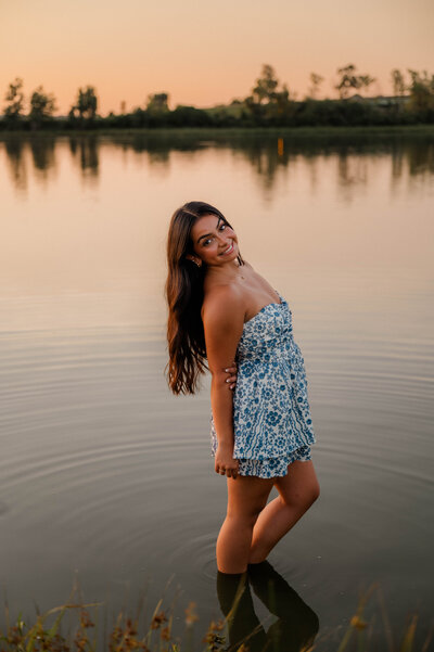 Teenage girl places both hands in her hand and smiles.