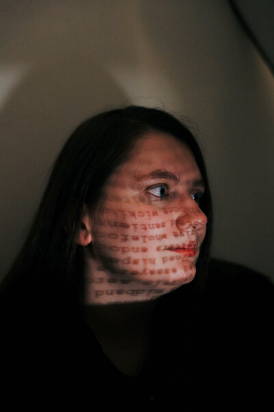 KP poses in front of a wall with words displayed on her face