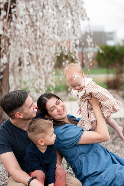 Family of four smiling at each other in coordinating outfits during Utah Family Photos.