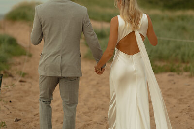couples walk on beach for engagement shoot in pei
