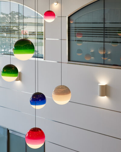 Several blue, green, red, and white tritone globe pendant lights hanging from the ceiling