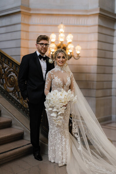 Bride and groom portrait at city hall staircase with white orchid bouquet