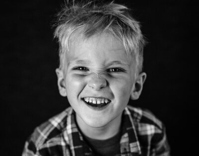 A young boy laughs and wrinkles his nose in delight during his fine art school portrait session by Kate Simpson Photography.