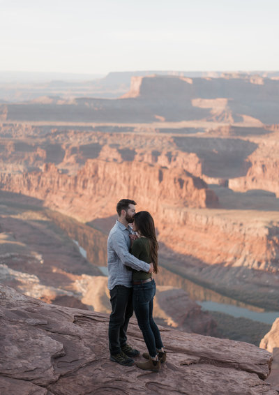 man and woman standing on edge of grand canyon hugging