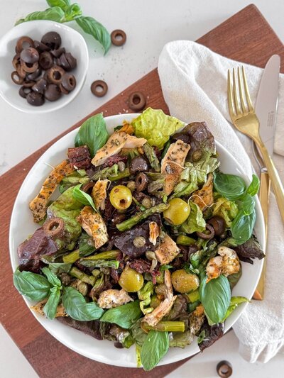 A mediterranean salad bowl with leftover asparagus spears and black olives.