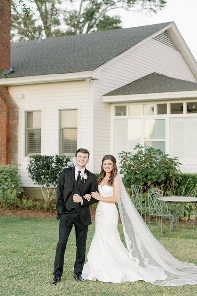 Wedding couple smiling in front of a house