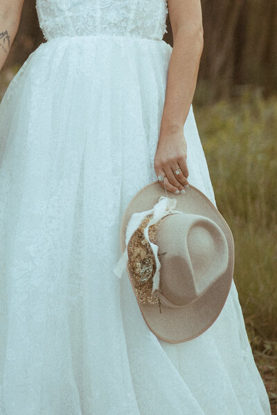 bride holding bohemian hat with dried florals