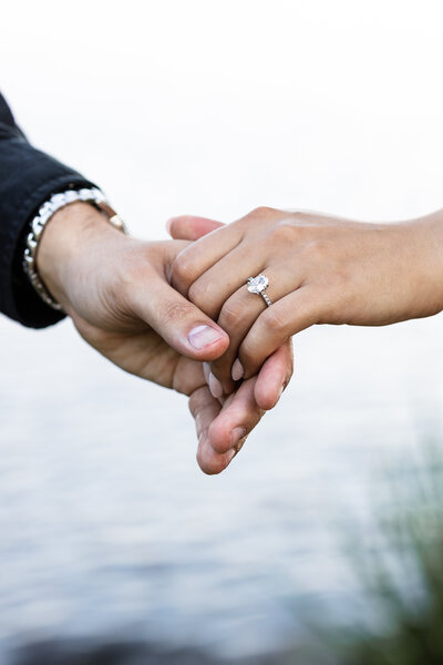 Couples hands holding showinf an engagement ring