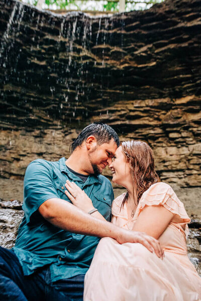 A couple cuddles under a waterfall during their elopement photography in a national park in Montana.