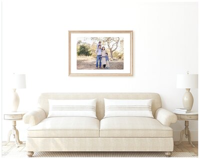 Mockup showing large family portrait displayed as wall art above beige couch in living room