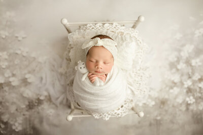 Airy newborn photograph with gentle highlights, minimal styling, and soft neutrals for a modern fine-art look.