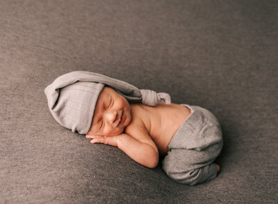 A newborn baby smiles during his newborn photoshoot.