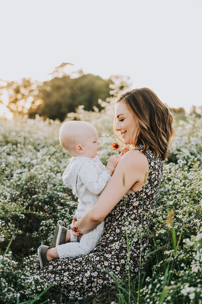 Mom holds toddler boy in a field of wildflowers during family session