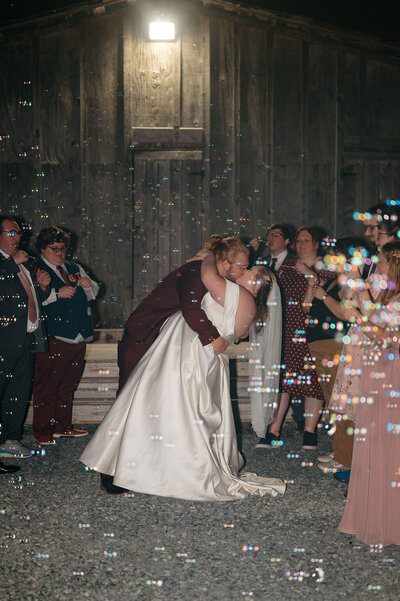 Newlyweds kissing during bubble exit with guests