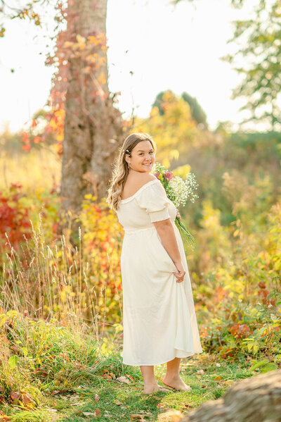 Girl in white dress holding a bouquet for her cottagecore high school senior portraits