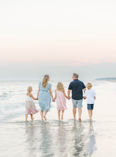 Hilton Head Photographers, Lamp and Light Photography capturing a family's beautiful moments on the beach as they walk hand-in-hand at sunset.