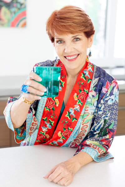 Interior Design Coach Melissa Galt holds up cocktail glass to offer a cheers