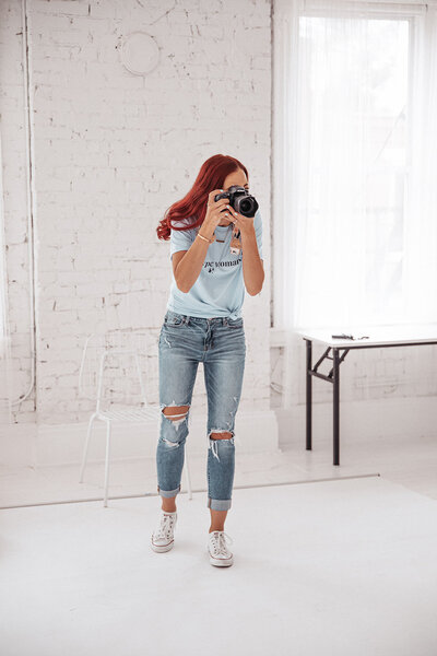 photographer wearing a blue shirt and jeans is taking a picture with her camera