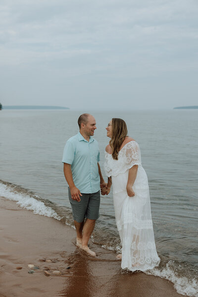 bride and groom walking on a beach playing in the water on the apostle islands