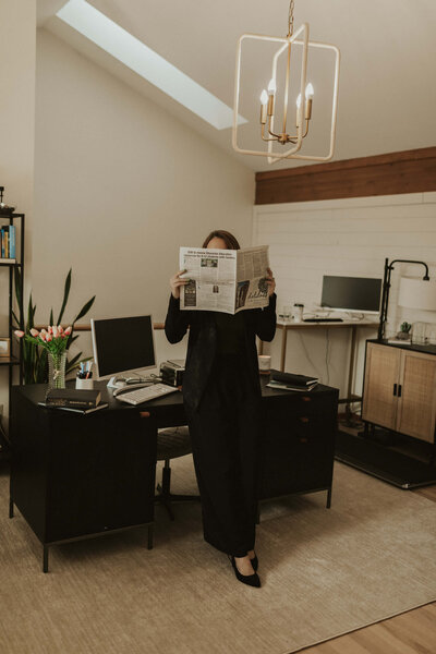 Career coach with newspaper leaning against desk