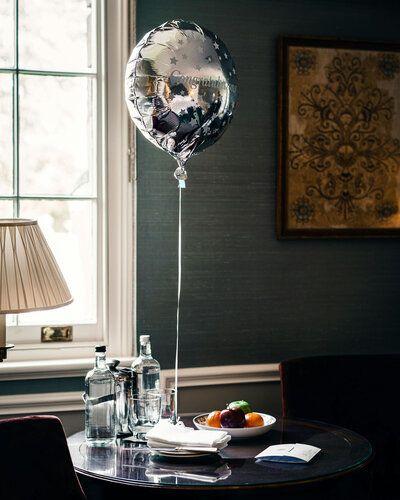 Silver balloon is sitting on a table in front of a window