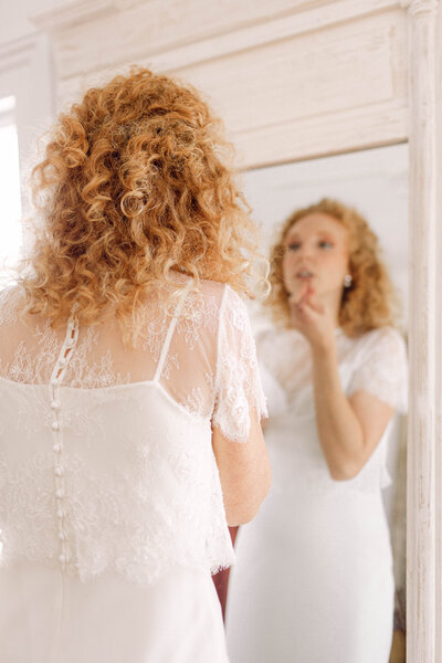 Bride applying lipstick in the mirror while getting ready for her intimate backyard wedding ceremony in Richmond, Virginia, captured in soft natural light.