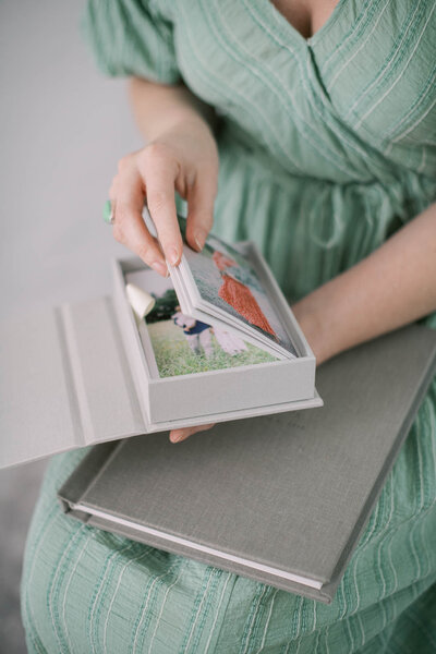 a wooman holding a custom linen print box filled with pictures by richmond va family photographer