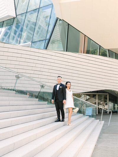 tall angle shot of bride and groom in front of a church with their classic getaway car