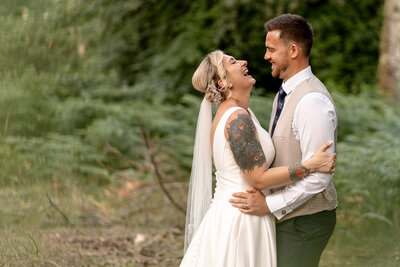 Groom giving bride a piggyback ride at outdoor reception