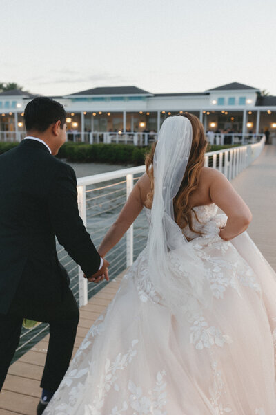 couple running away from camera down a dock