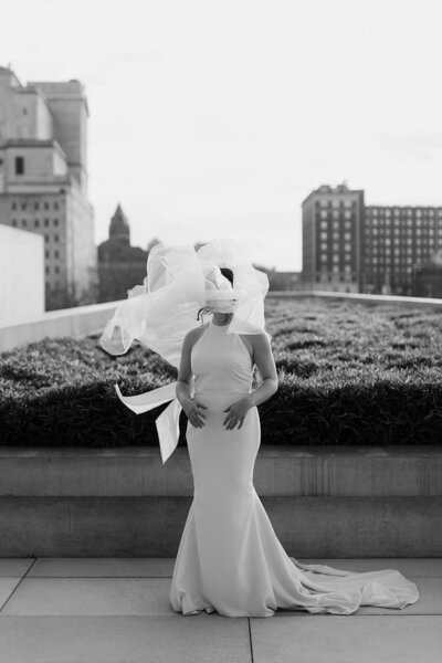 Black and white image of bride with veil blowing over her face