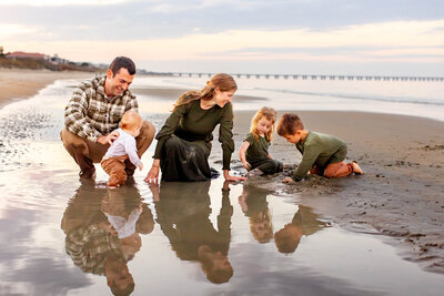 A playful storytelling session by Brooke Tucker showing parents and children laughing and exploring together at the shoreline in Hampton Roads, Virginia