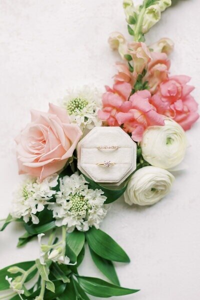 Close-up of a floral wedding bouquet with engagement and wedding rings nestled among the blooms, photographed by Milwaukee wedding photographer Emily Barbara.