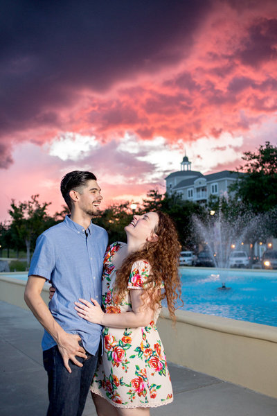 couple laughs in front of a brilliant sunset at The Market Common