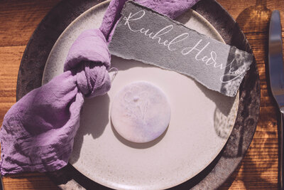 Stoneware Plates with purple napkin, calligraphy place name, biscuit favour