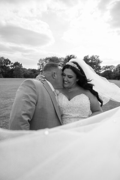 Groom kissing his Bride on the cheek with veil photo at Heaton Park, Manchester