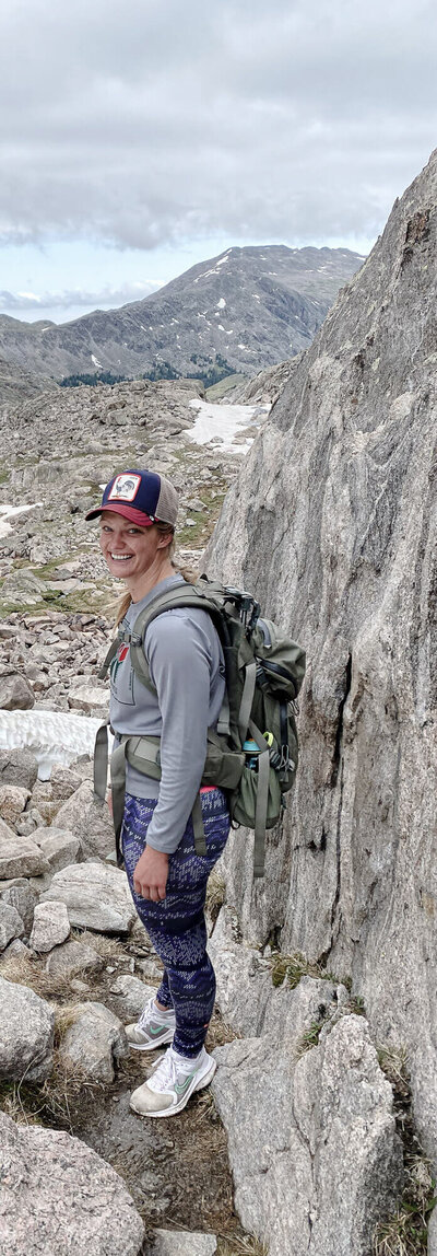 girl hiking on rocks wearing a backpack