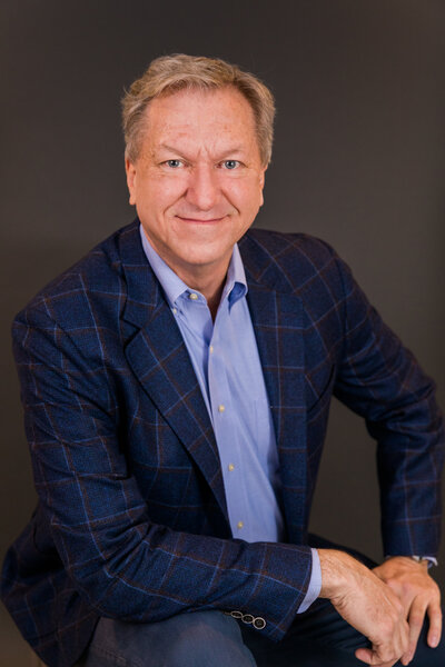 man wearing blue shirt and jacket sitting in front of a thunder gray backdrop in studio Atlanta Laure photography branding headshot