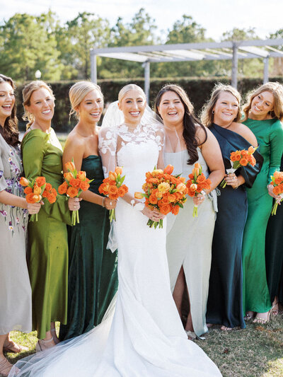 Bride surrounded by her bridesmaids all holding orange bouquets