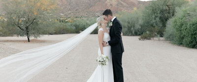 A couple kissing at sunset during their Scottsdale, Arizona wedding, with the warm desert landscape and golden sky creating a romantic backdrop.