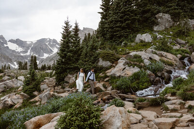 photo of bride and groom hiking through a forest of evergreens taken by Adventure wedding photographer