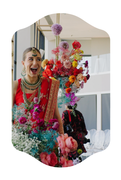 Snapshot from a Boston wedding film of the bride smiling with a backdrop of vibrant flowers